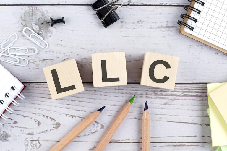 LLC text on wooden block with office tools on the wooden background